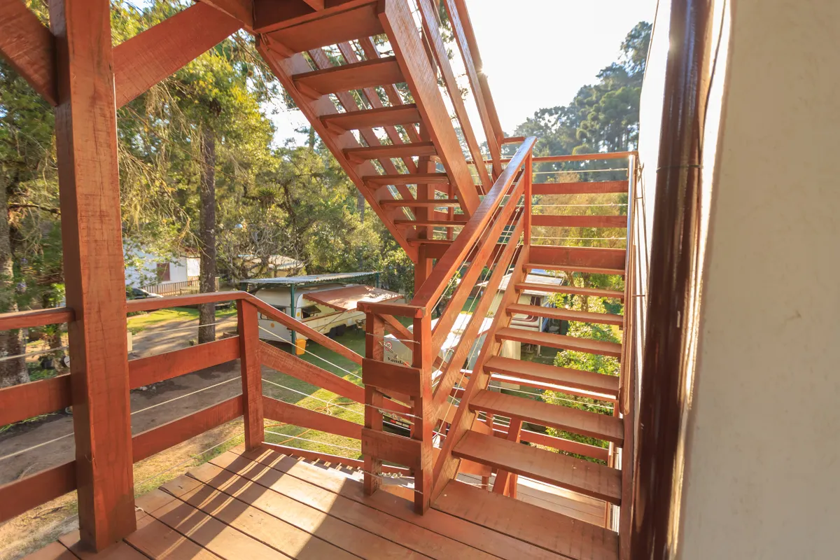 Wooden staircase in sunlight surrounded by trees on a wraparound deck, Omaha metro