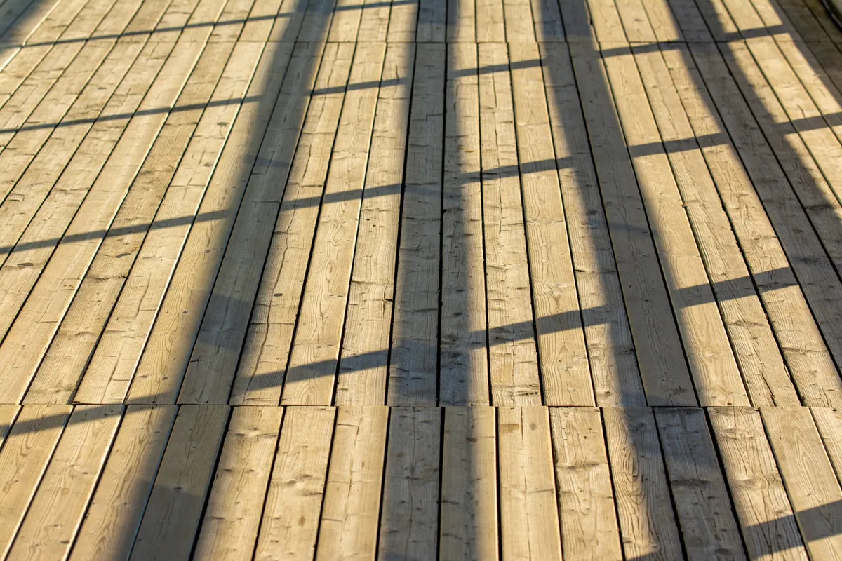 Wooden deck with railing lit by sunlight showing repaired boards, Sarpy County